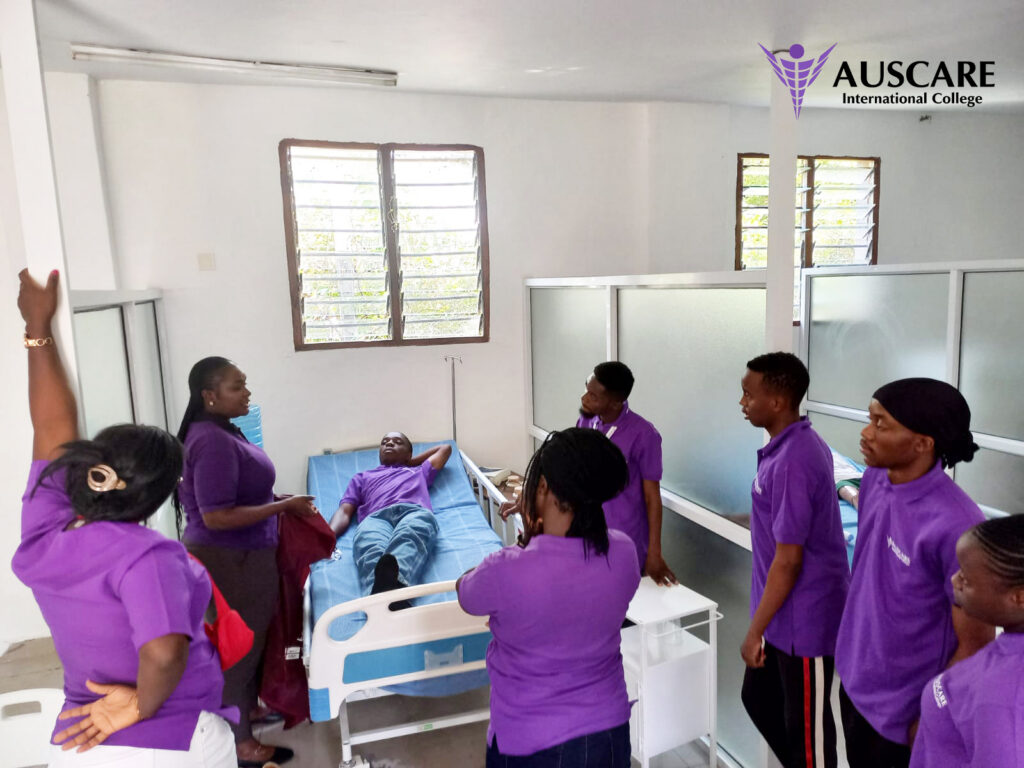 Group of people in purple uniforms around a patient lying in a hospital bed in a bright ward with windows