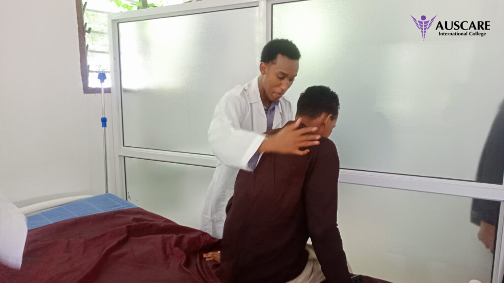 Medical professional in a white coat consoles a seated patient in a clinic, AUSCARE logo visible in the top right.